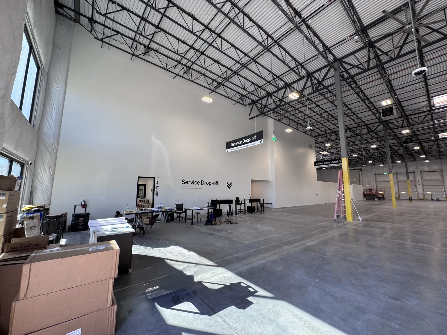 commercial-15 Large, empty warehouse interior with tables labeled "Service Drop-off" and boxes near the entrance.