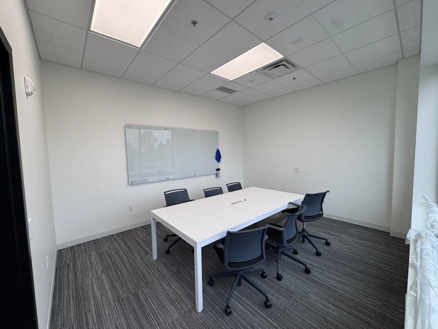 commercial-20 Small conference room with a white table, six chairs, and a whiteboard on the wall.