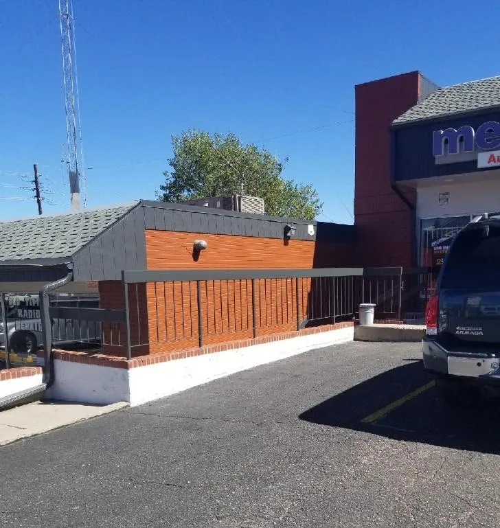 A wheelchair ramp leads up to a wall with no door, making it inaccessible. A car is parked nearby.