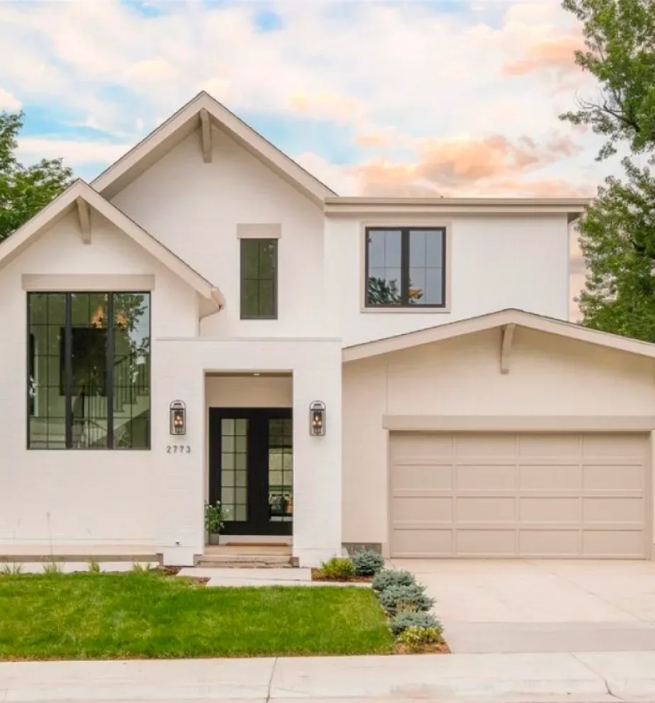 Modern two-story white house with large windows, double garage, and small green front lawn.