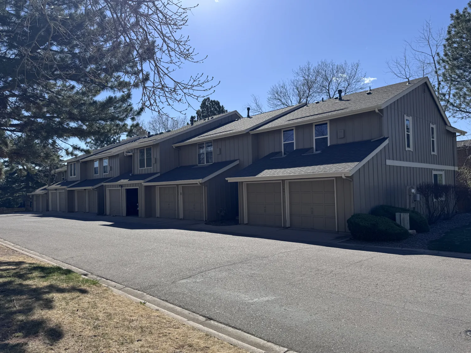 hoa-5 A row of townhouses with garages on a sunny day, shadows cast on the quiet street.