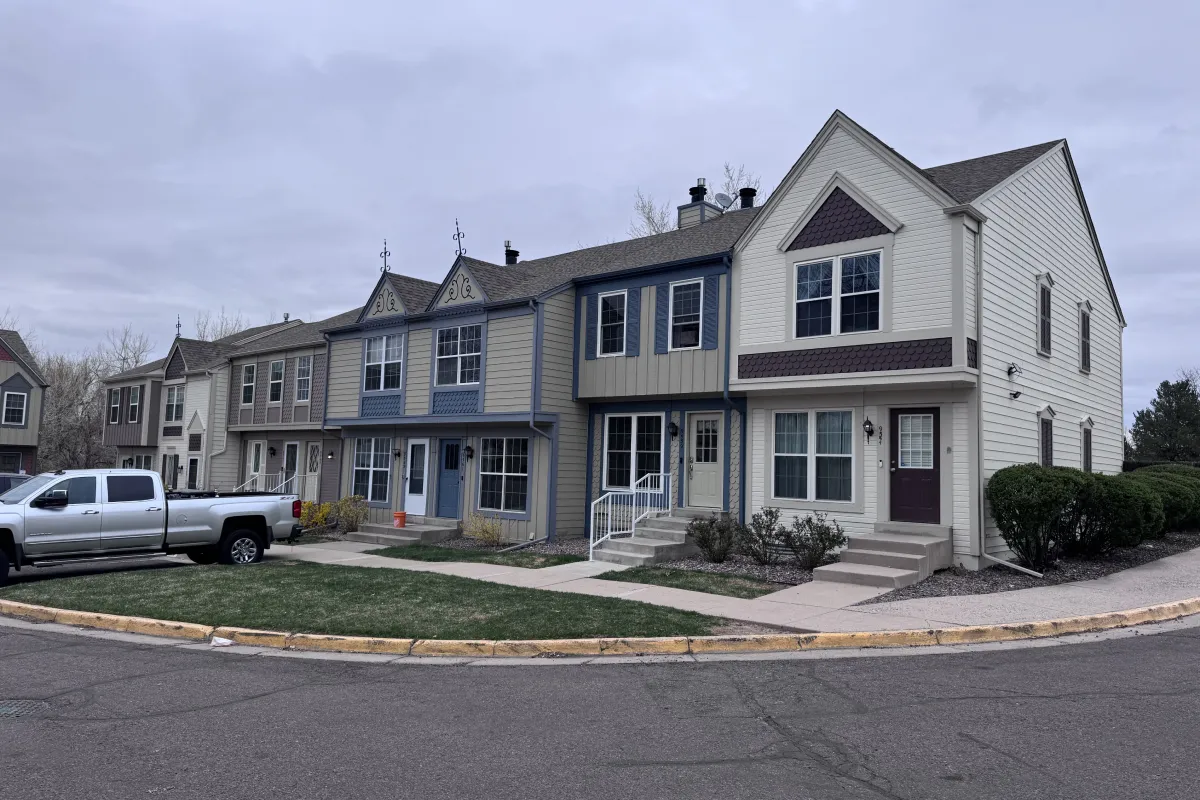 Row of modern townhouses with a white pickup truck parked on the street under a cloudy sky.