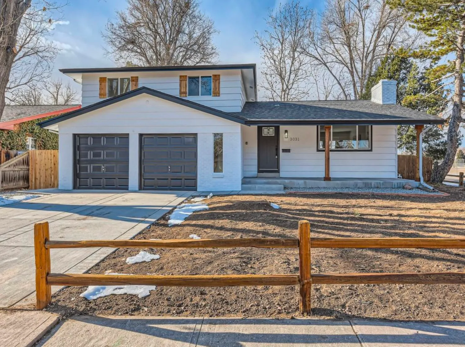 residential-exterior-14 Two-story house with a double garage, white siding, and a fenced front yard with little snow.
