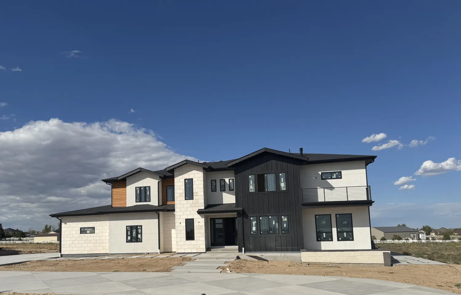 residential-exterior-24 Modern two-story house with dark and light siding, large windows, and a clear blue sky in the background.