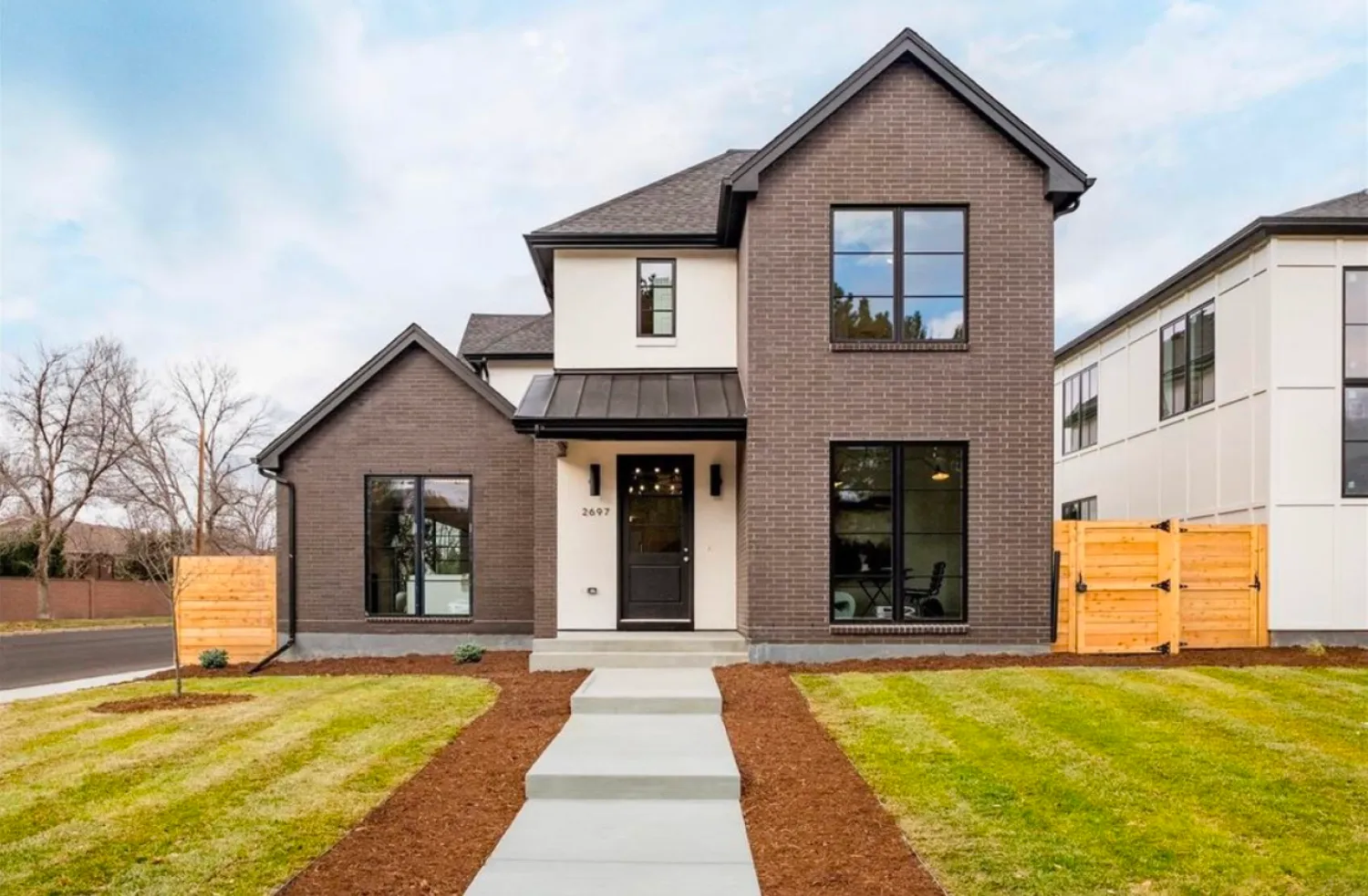 residential-exterior-4 Modern two-story house with black trim, large windows, and a neatly landscaped front yard and walkway.