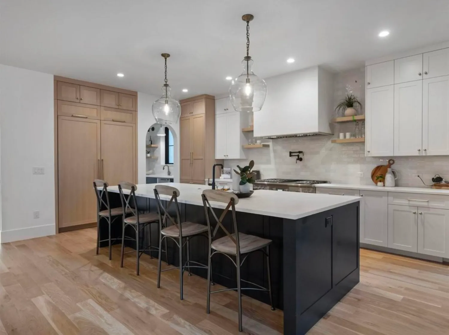 residential-interior-12 Modern kitchen with pendant lights, large island, wooden floor, and a mix of white and wood cabinets.