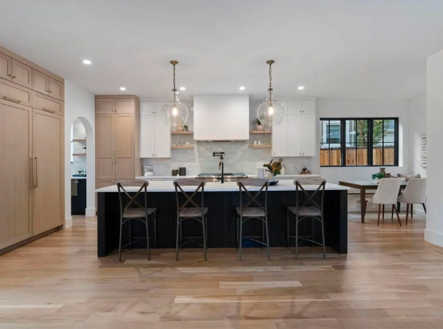 residential-interior-13 Modern kitchen with island, four chairs, pendant lights, wood floors, and light cabinets.