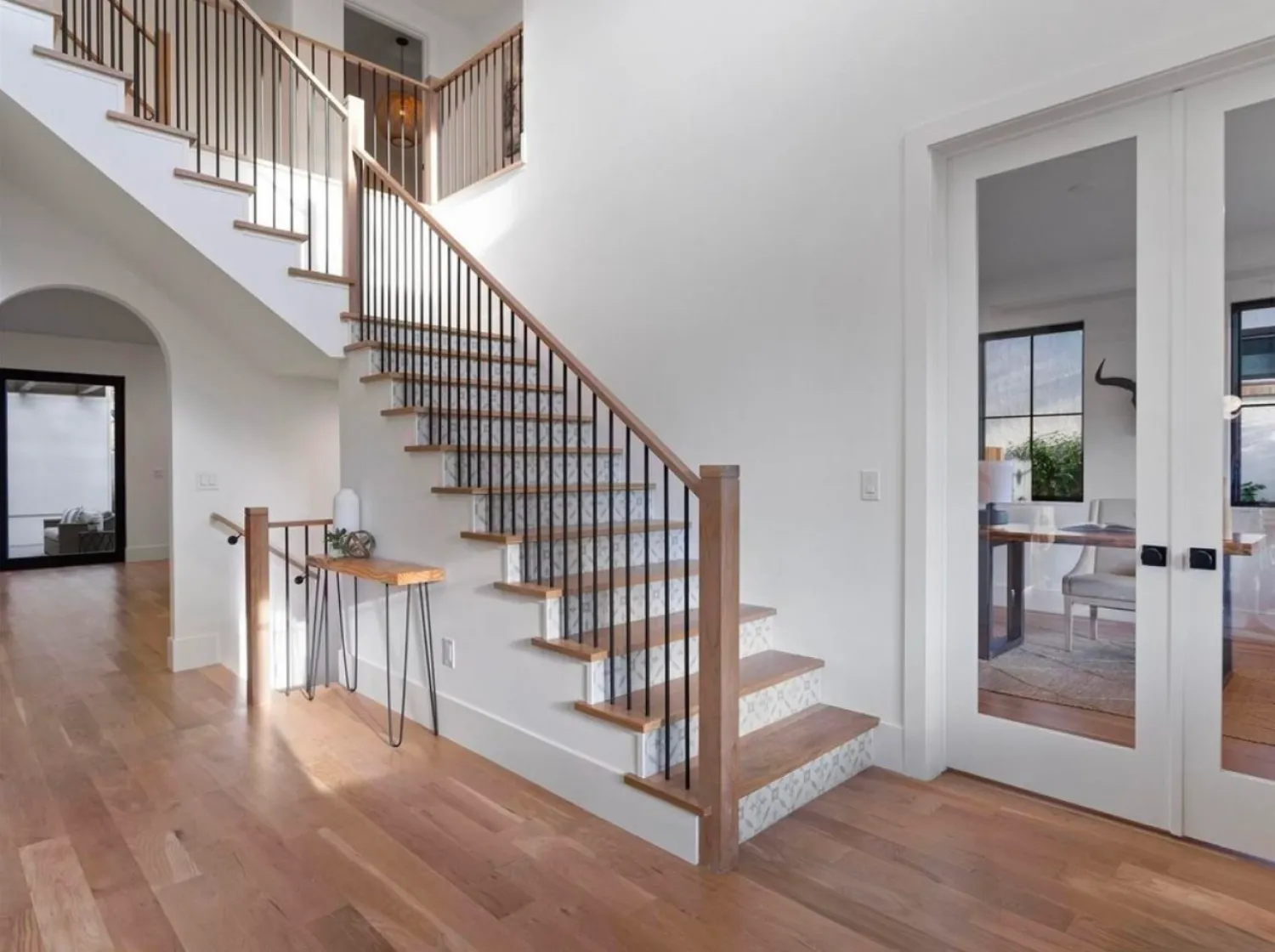 residential-interior-15 Modern home entryway with wooden stairs, glass doors, and light wood floors, featuring minimal decor.