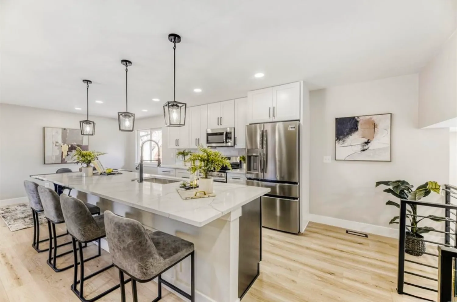 residential-interior-17 Modern kitchen with marble island, gray chairs, stainless appliances, pendant lights, and abstract art.