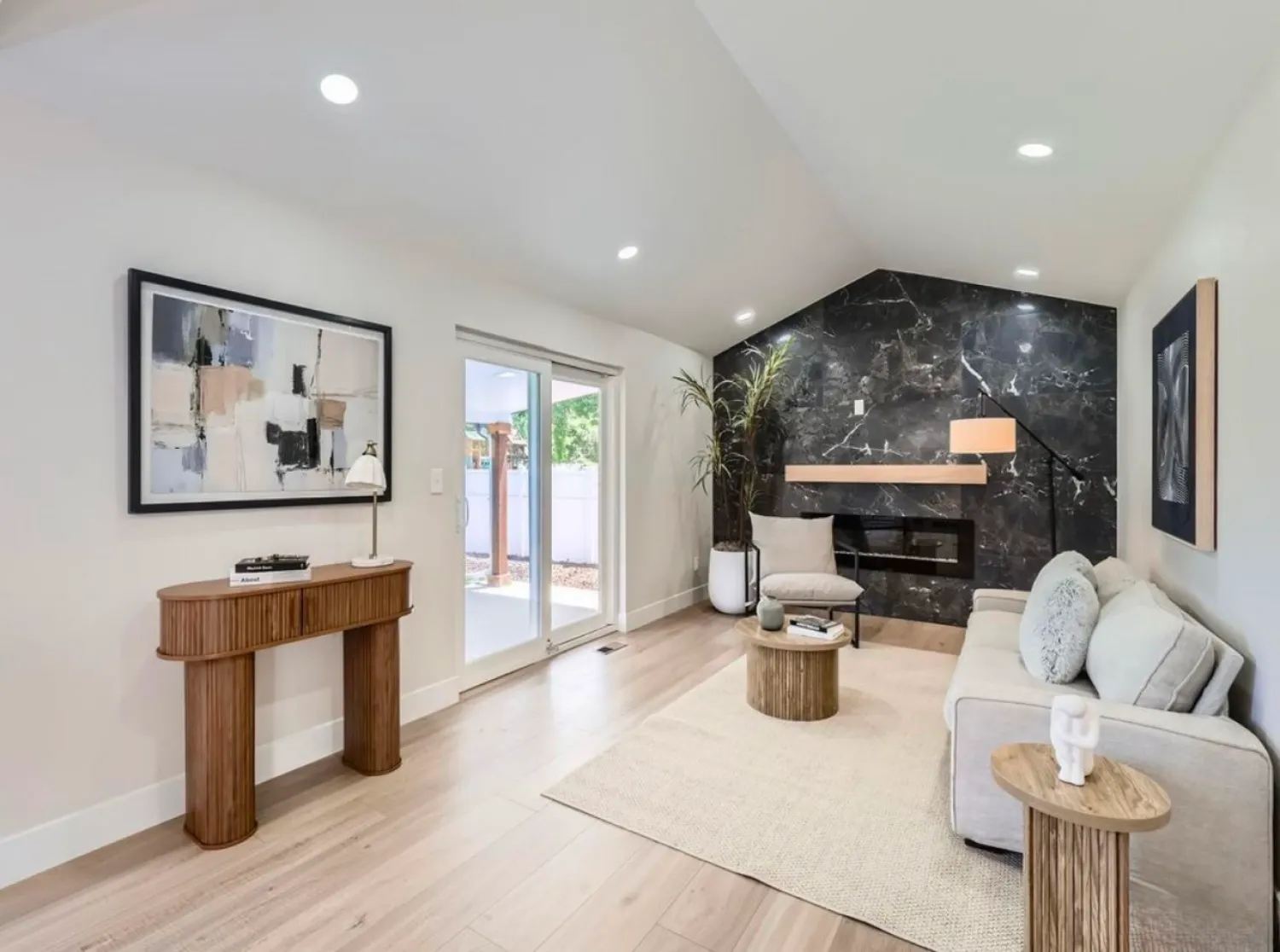 residential-interior-20 Modern living room with beige sofa, black marble accent wall, abstract art, and wooden furniture.