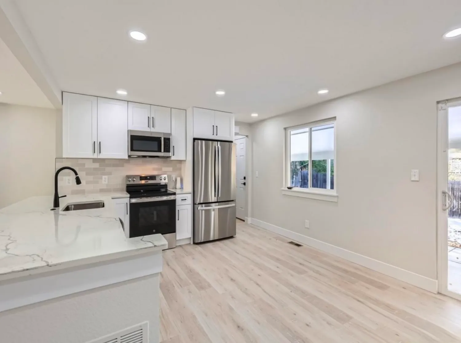 residential-interior-28 Modern kitchen with white cabinets, stainless steel appliances, and light wood flooring.