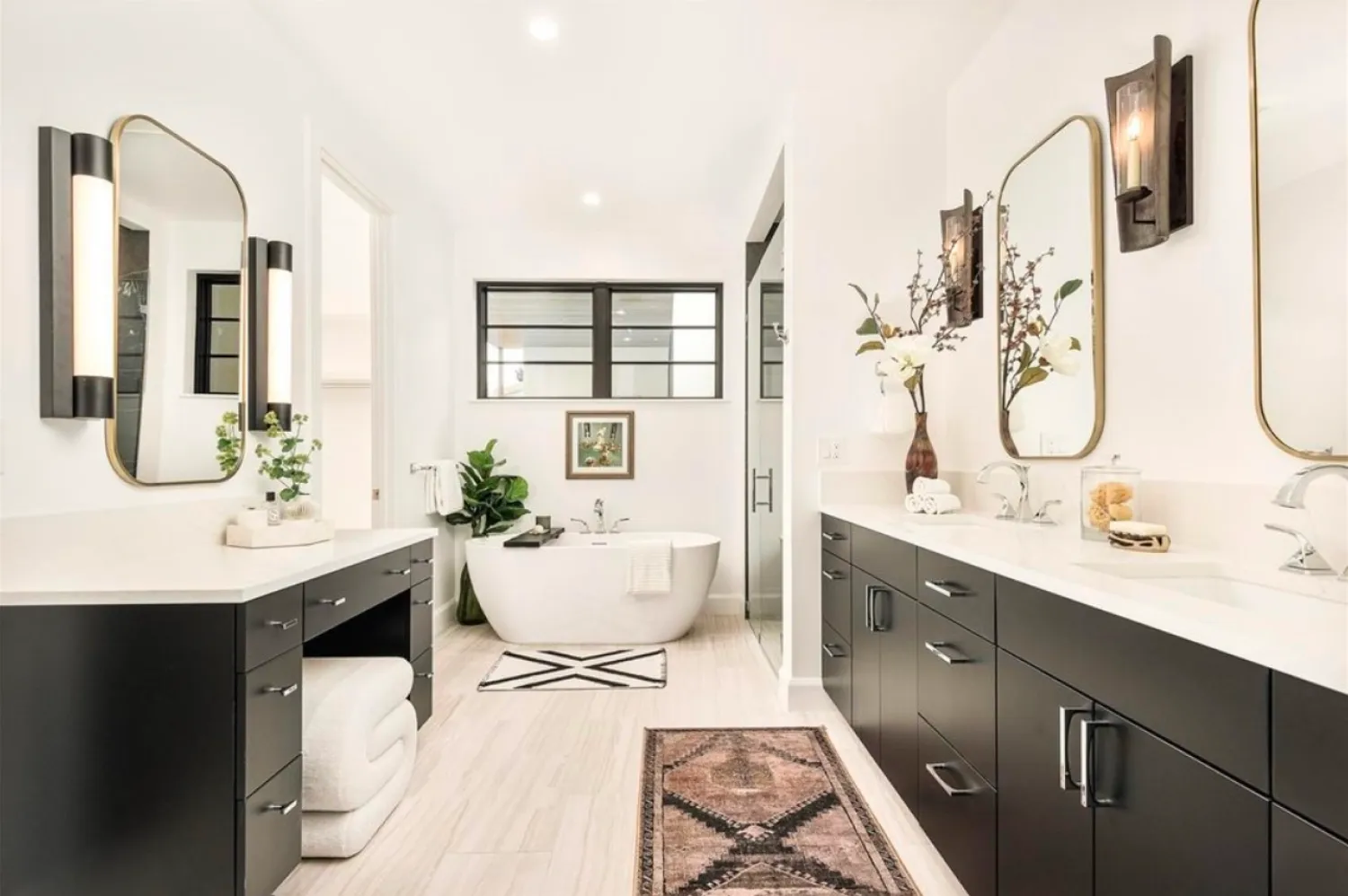 residential-interior-4 Modern bathroom with black cabinets, double sinks, a white tub, large mirrors, and decorative lighting.