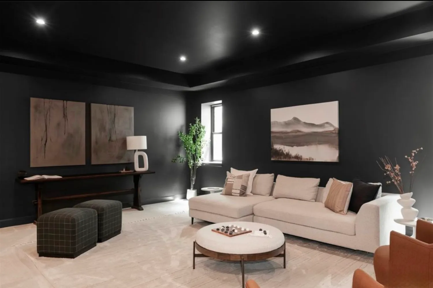 residential-interior-49 Modern living room with black walls, white sectional sofa, round coffee table, art, and indoor plant.