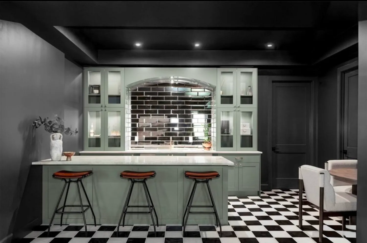residential-interior-50 Modern kitchen with black and white checkered floor, mint cabinets, bar stools, and black subway tile backsplash.