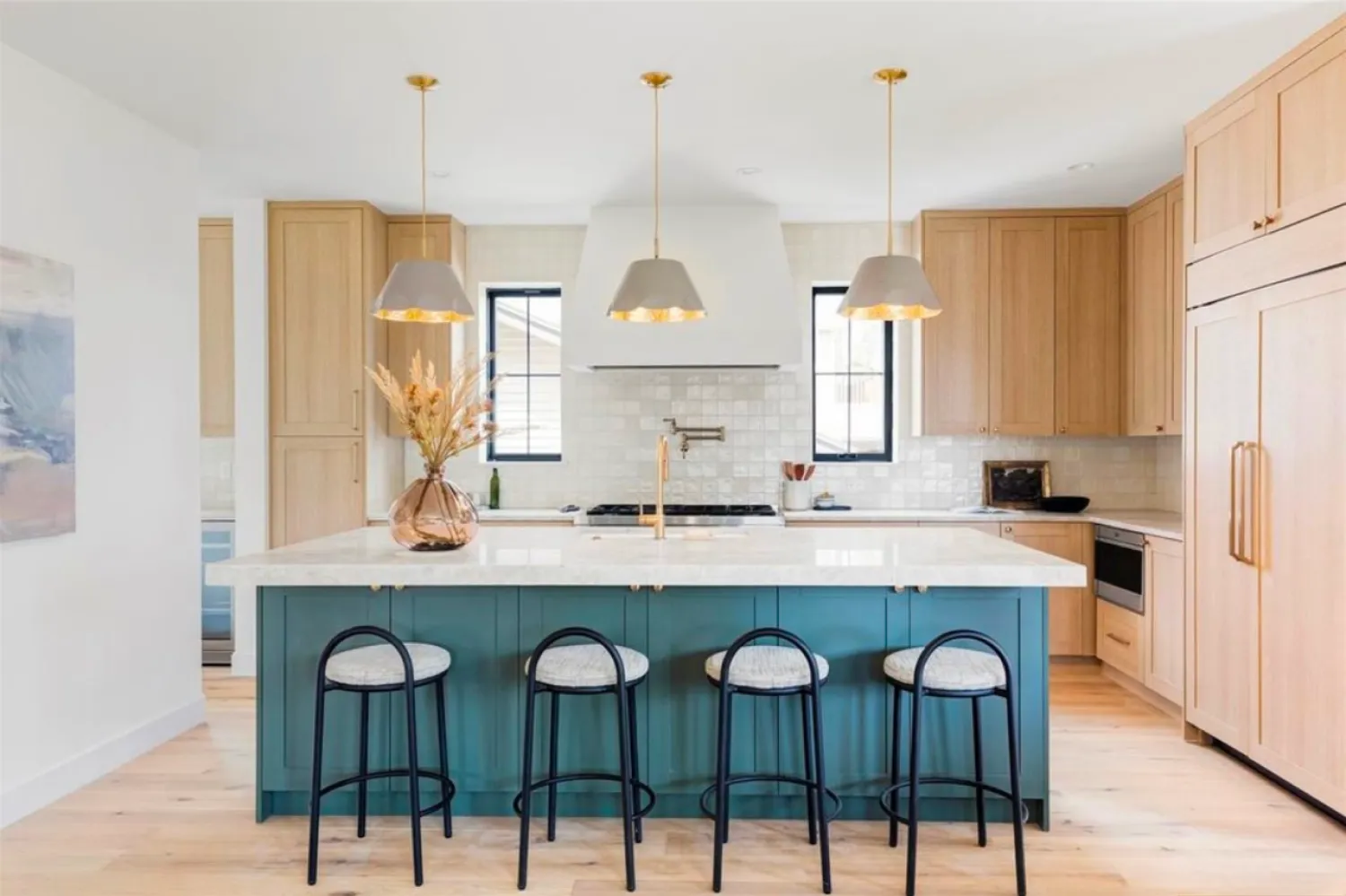 residential-interior-51 Modern kitchen with a blue island, wooden cabinets, pendant lights, and four barstools.