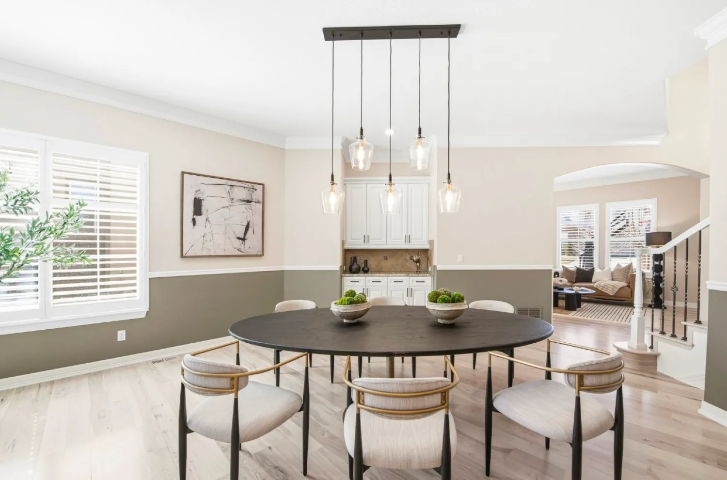 residential-interior-60 Modern dining room with round black table, six chairs, pendant lights, and neutral décor.