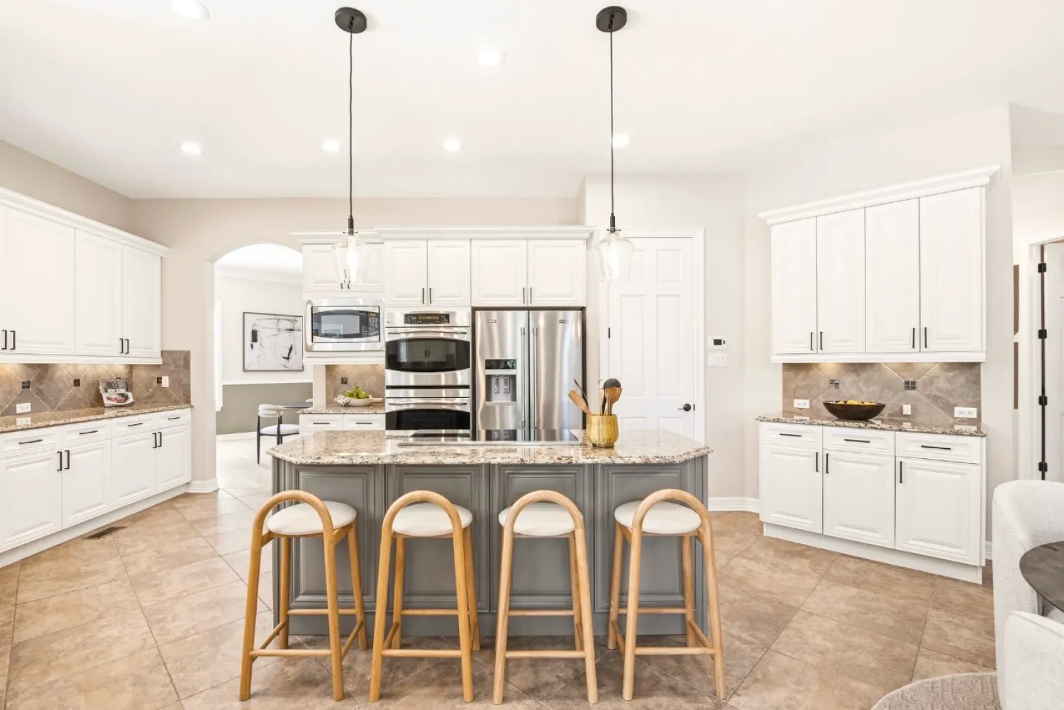 residential-interior-61 Modern kitchen with white cabinets, stainless steel appliances, and an island with four wooden barstools.