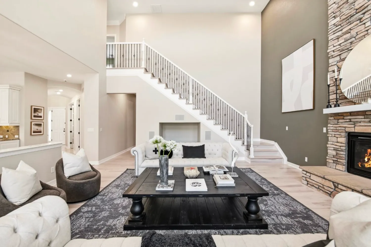 residential-interior-64 Modern living room with neutral tones, a black coffee table, fireplace, and a staircase in the background.